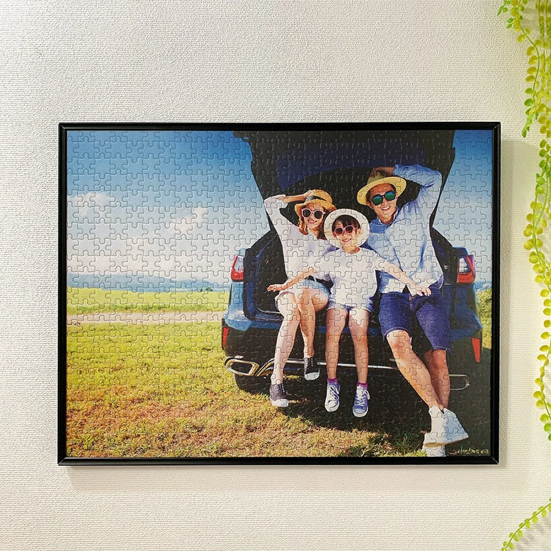 黒いアルミフレームに入れた家族の写真パズルを壁に掛けた実物例
